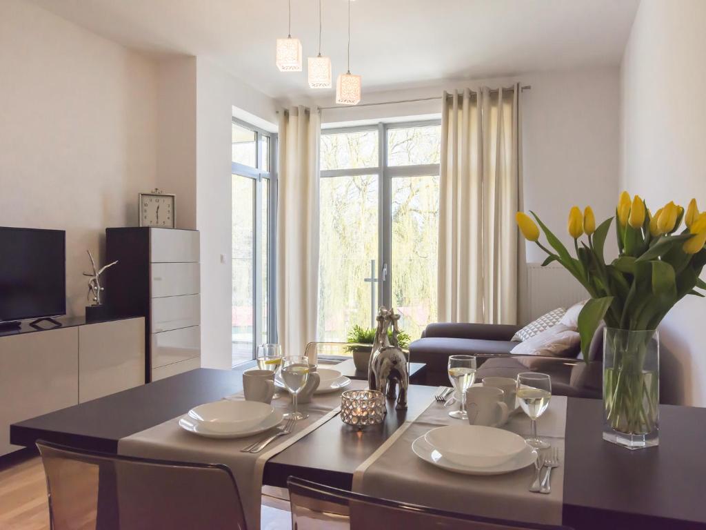 a living room with a dining room table with yellow flowers at VacationClub - Diune Apartment 26 in Kołobrzeg
