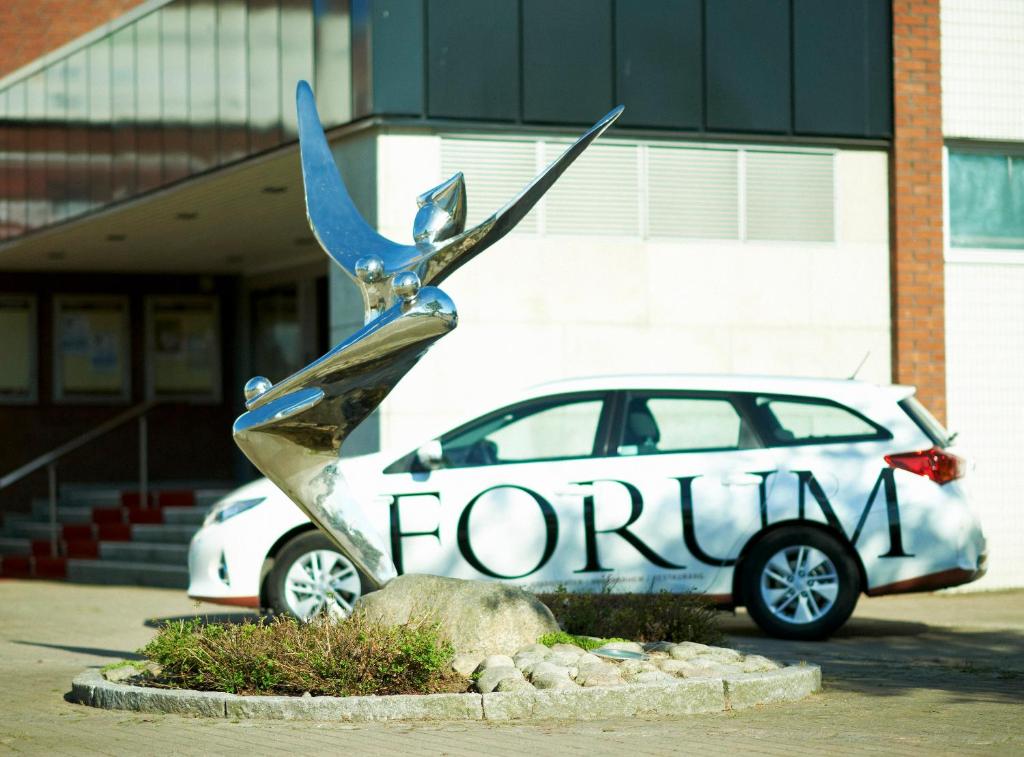 una statua di un paio di forbici davanti a un'auto di STF Vandrarhem Oscar a Oskarshamn