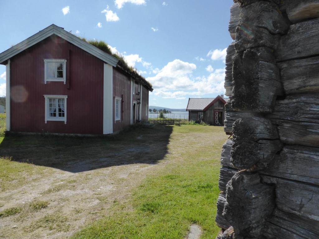 a red and white building next to a stone wall at Vestre Sorken Feriegard in Drevsjø