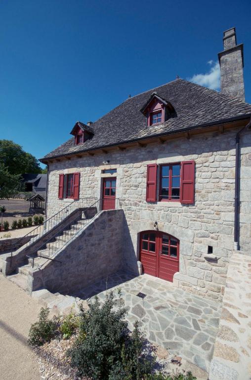 une maison en pierre avec des portes rouges et un escalier dans l'établissement La Maison Des Jardins, à Auriac