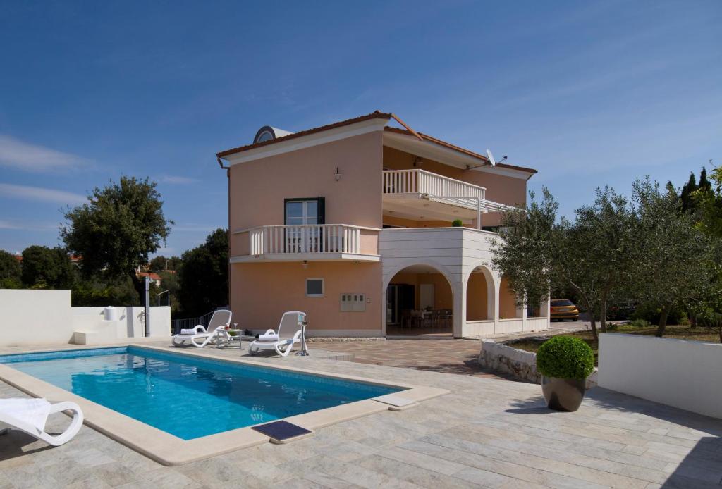 a villa with a swimming pool in front of a house at Villa Omnes in Ražanj