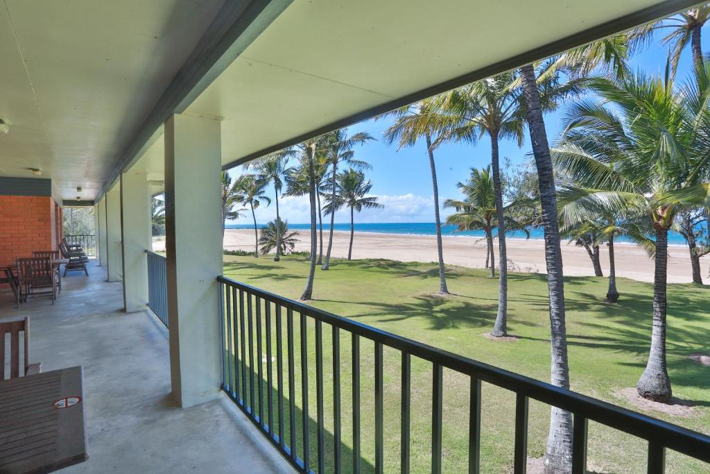 een balkon met uitzicht op het strand en de palmbomen bij Sarina Beach Motel in Sarina