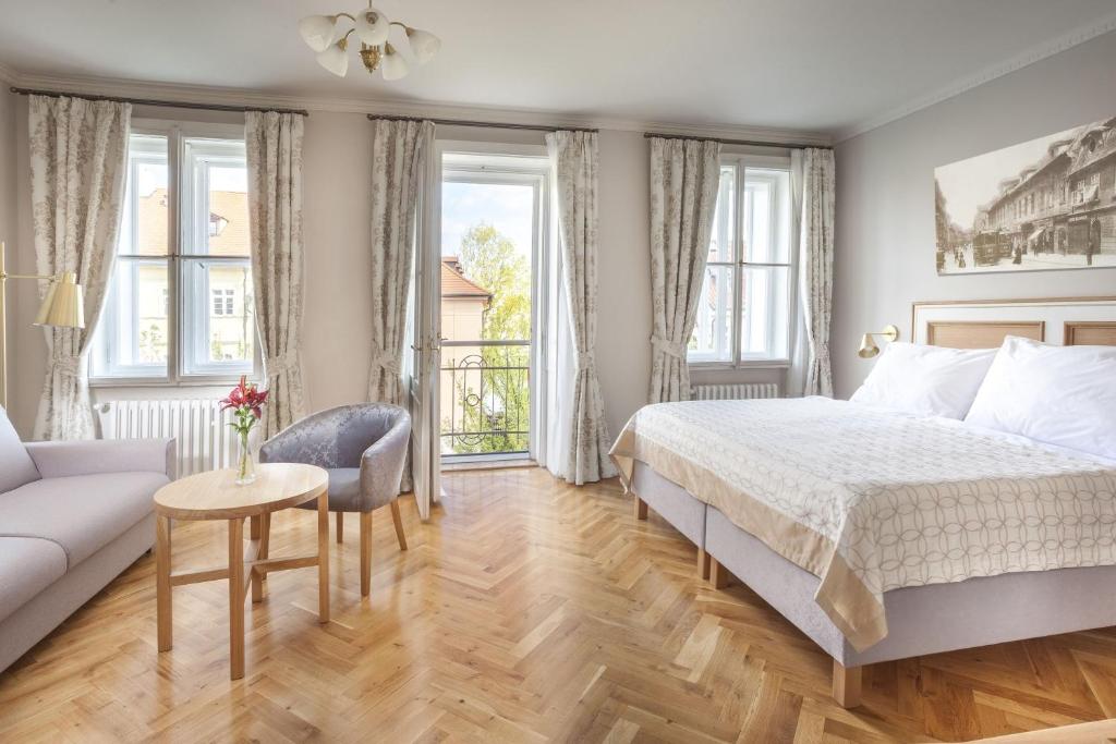 a bedroom with a bed and a couch at Hotel At the Golden Scissors in Prague