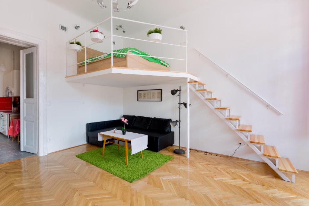 a living room with a black couch and a staircase at F4 Fiumei Apartment in Budapest