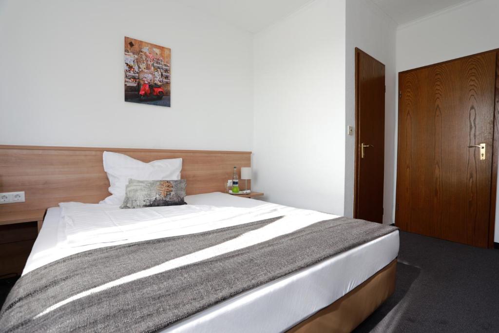 Schlafzimmer mit einem großen weißen Bett mit einem Kopfteil aus Holz in der Unterkunft Hotel zwei&vierzig in Vallendar