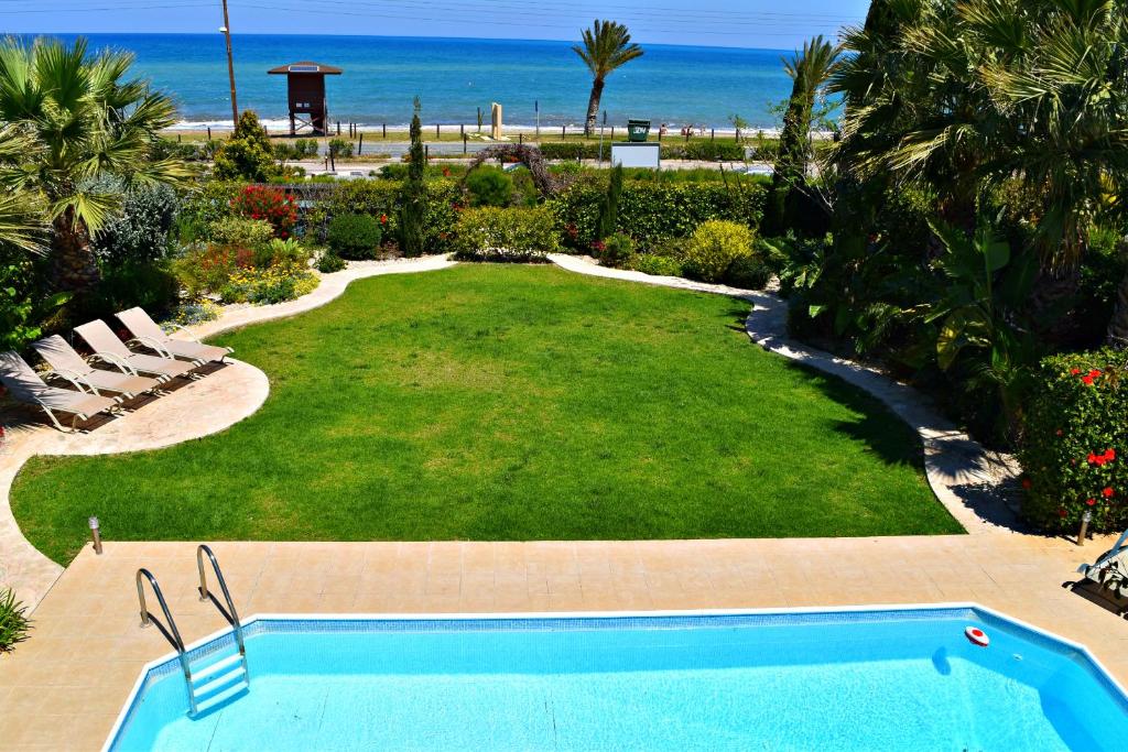 a large yard with a swimming pool and the beach at Latchi Beach Front Villa - Private Heated Pool - Amazing Uninterrupted Sea Views in Polis Chrysochous