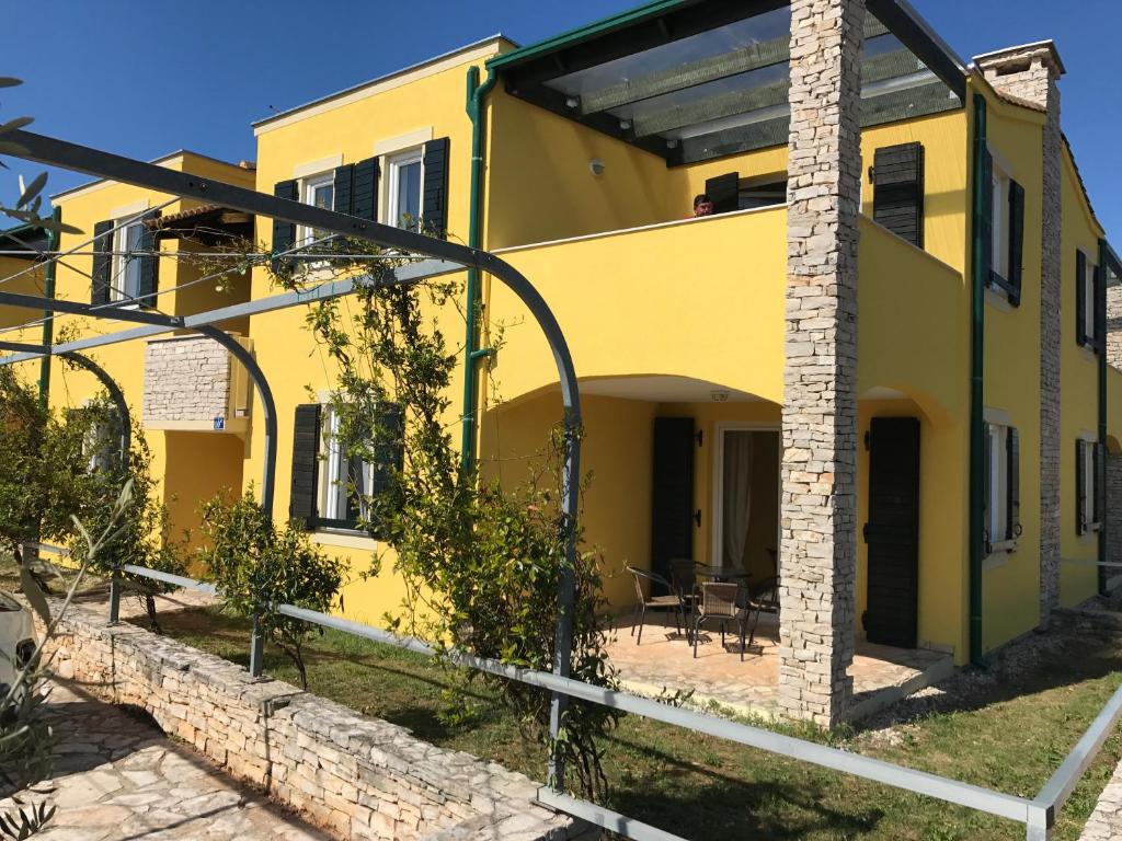 un edificio giallo con tavoli e sedie di fronte di Villas Faro a Bašanija (Bassania)