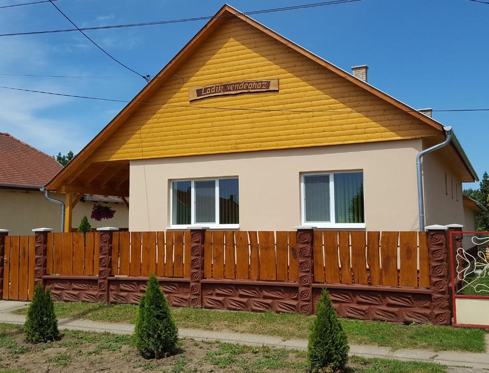 une maison avec une clôture en bois devant elle dans l'établissement Ladik Vendégház, à Tiszafüred