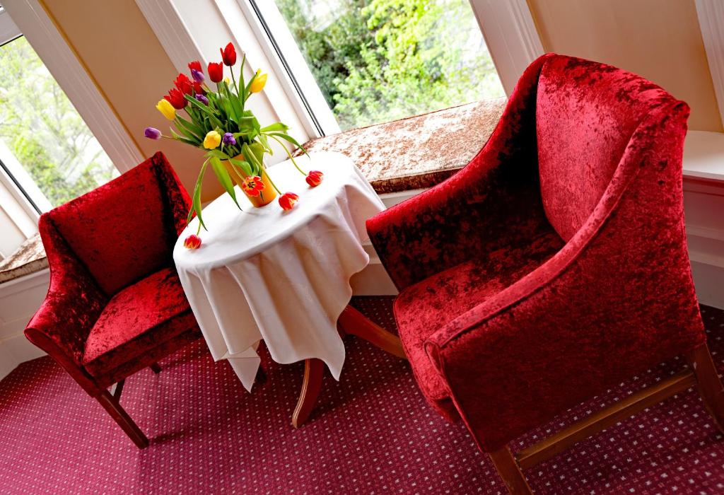 two chairs and a table with a vase of flowers at Gabriel House Guesthouse in Cork