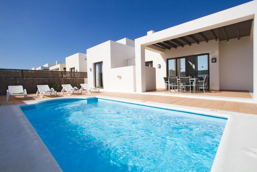 a villa with a swimming pool in front of a house at Ereza Villas Las Buganvillas in Playa Blanca