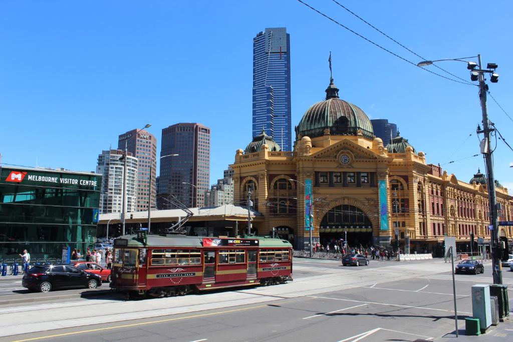 a red trolley in front of a building in a city at Flinders Street 238, CLEMENTS HOUSE at Federation Square, Melbourne, Australia in Melbourne
