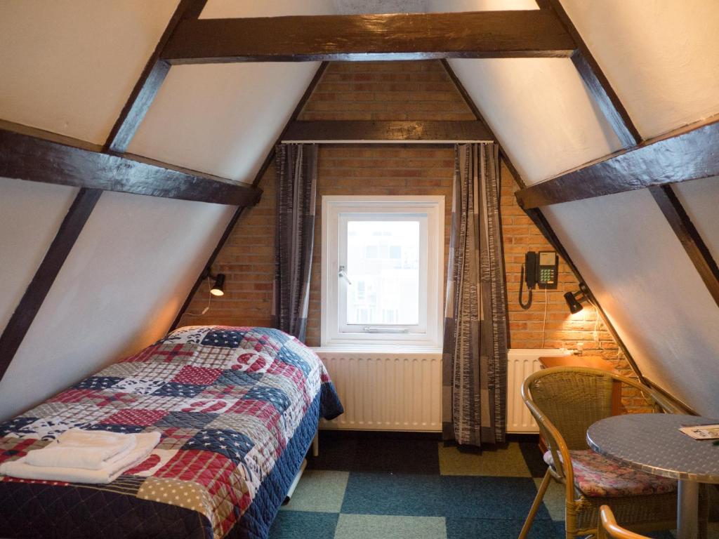 Habitación con cama, mesa y ventana en Hotel Adolesce, en Ámsterdam