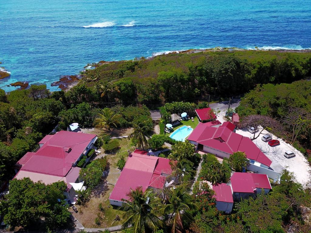 an aerial view of a resort with pink roofs and the ocean at La Rose du Bresil Marie-Galante in Capesterre-de-Marie-Galante