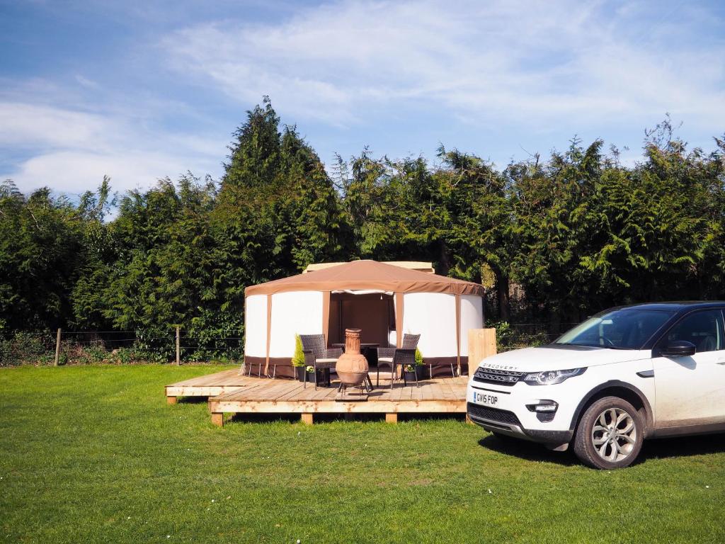 une voiture blanche garée devant un kiosque dans l'établissement Old Dairy Farm Glamping, à Emsworth