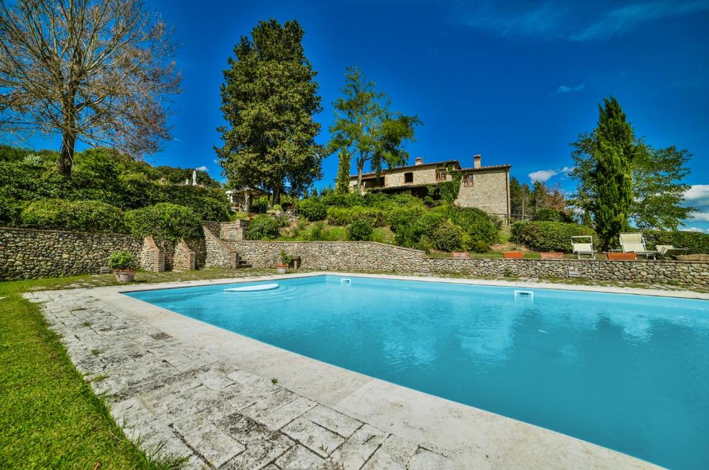 una piscina frente a una pared de piedra en Podere Casanuova, en San Gimignano