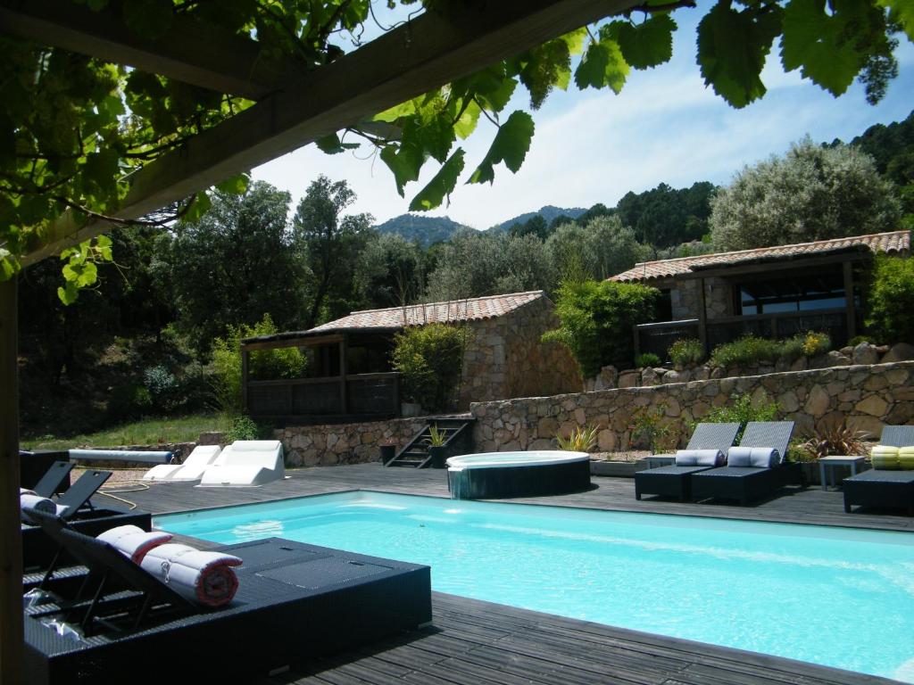 a swimming pool with chairs and a house at Les Jardins de Mathieu in Porto-Vecchio