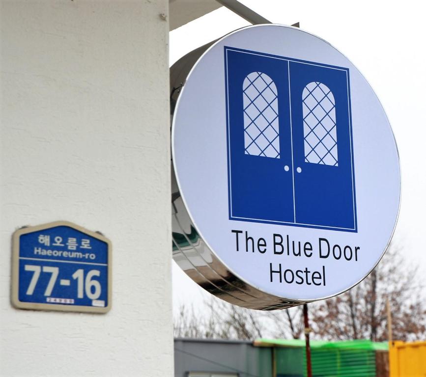 a sign for the blue door hospital next to a building at Blue Door Hostel Guesthouse in Sokcho