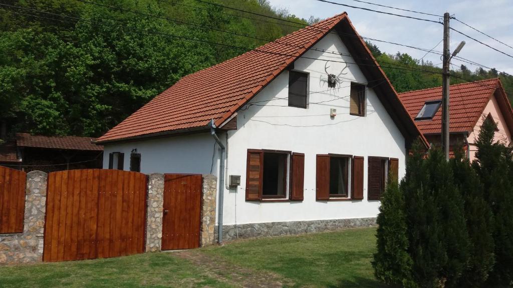 a white house with a red roof and a fence at Casa Sasca Montana in Sasca Montană