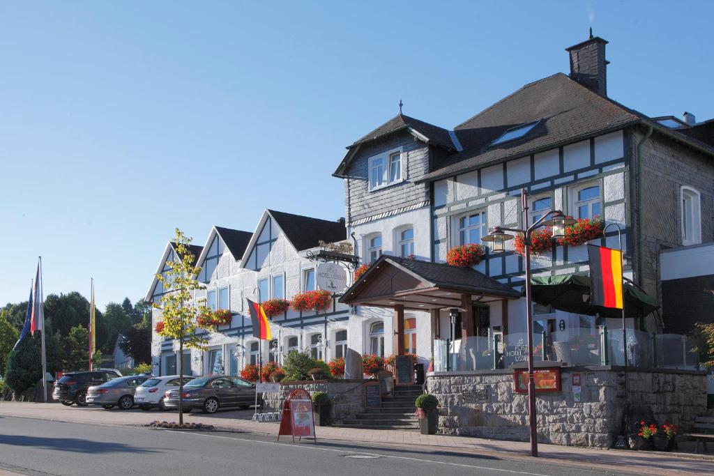 a row of houses on a city street with flags at Ringhotel Posthotel Usseln in Willingen