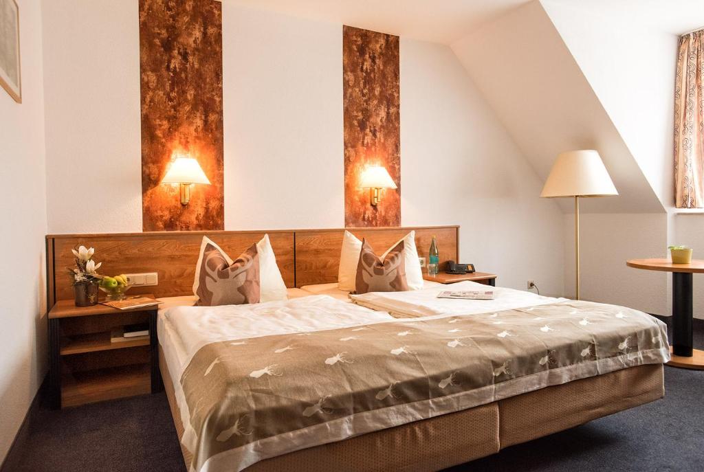 a hotel room with a bed and two lamps at Hotel Zum Hirsch in Römhild