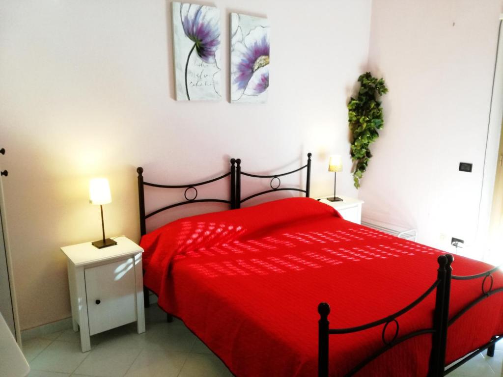 una camera con letto rosso e 2 comodini di B&B Quasimodo a Caltagirone