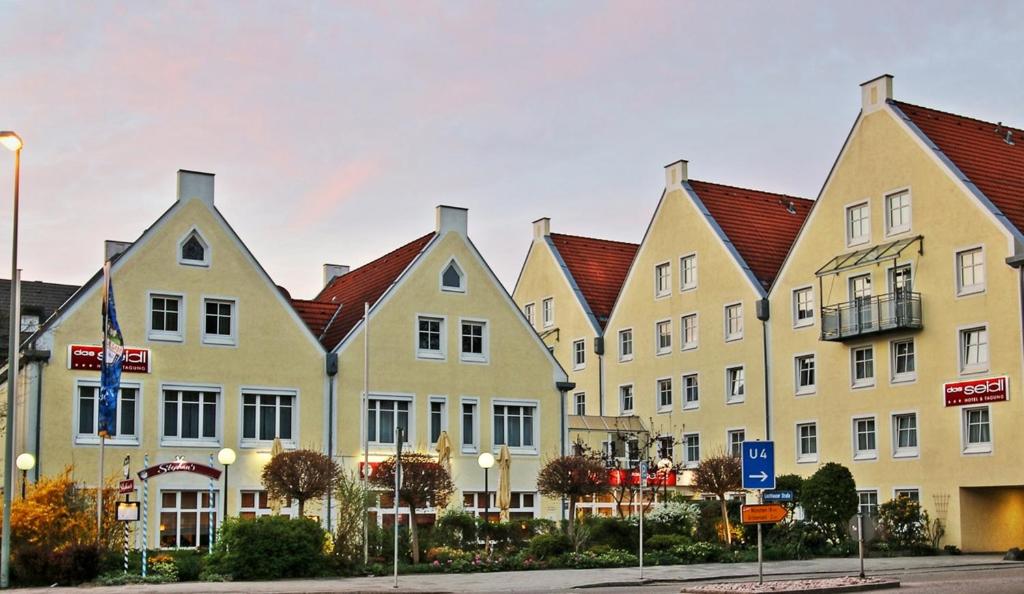 a row of yellow buildings with red roofs at das seidl - Hotel & Tagung - München West in Puchheim