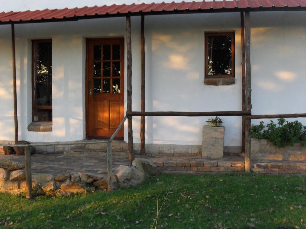 una casa bianca con porta in legno e finestre di Jen's a Dullstroom