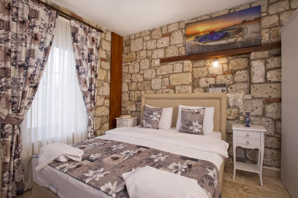 a bedroom with a bed and a stone wall at İncekara in Alacati
