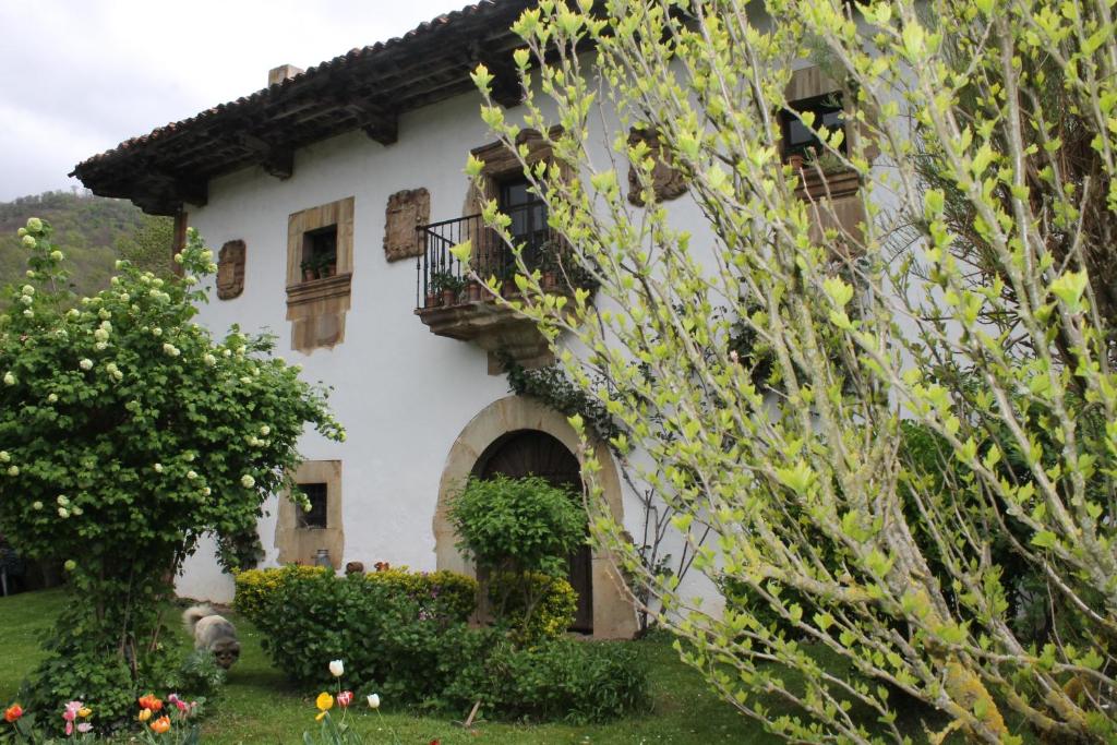 Cette grande maison blanche dispose d'un balcon et de fleurs. dans l'établissement Casona de Treviño, à Cosgaya