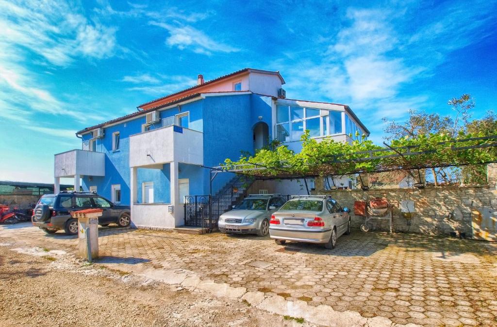a blue house with cars parked in front of it at Apartments Ivo 1328 in Fažana