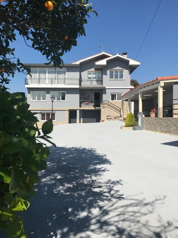 a white building with an orange tree in front of it at Hotel Sebreñu in Sebreño