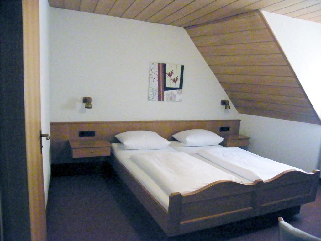 Schlafzimmer mit einem großen Bett mit einem Kopfteil aus Holz in der Unterkunft Pension Hofmann-Schmölzer in Rothenburg ob der Tauber