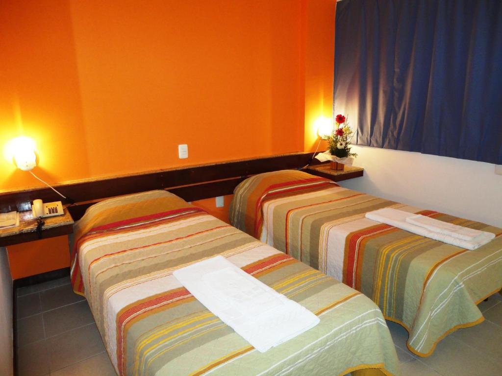 2 camas en una habitación de hotel con paredes de color naranja en Pisa Plaza Hotel, en Salvador