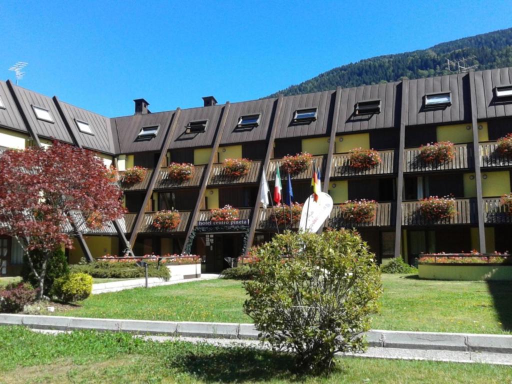 un grande edificio con una bandiera di fronte di Centro Pineta Family Hotel & Wellness a Pinzolo