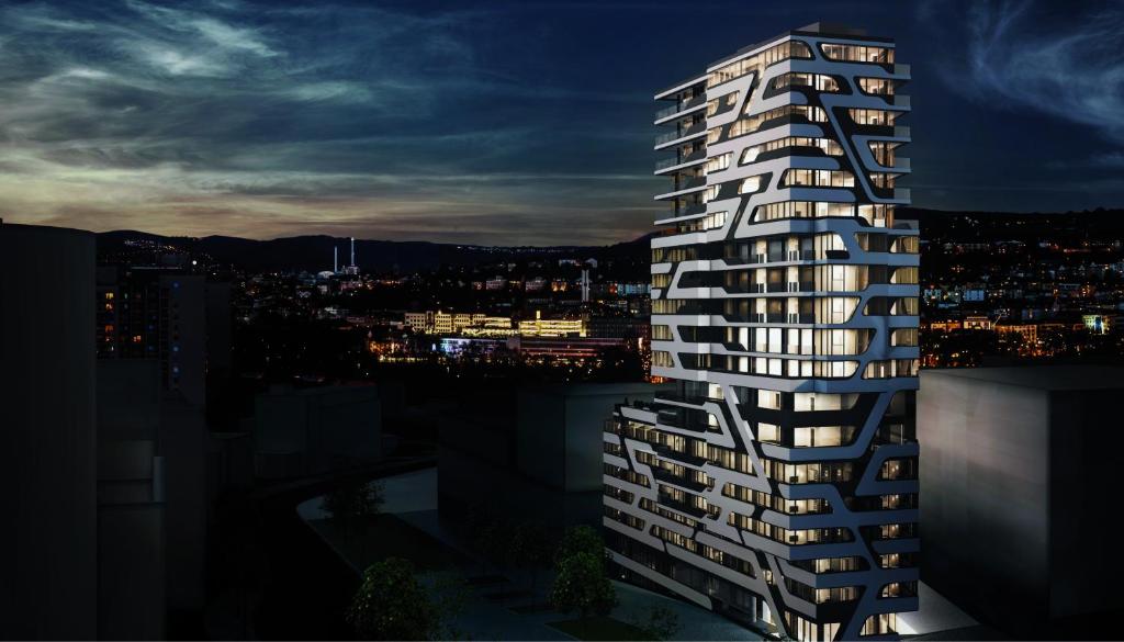 a tall white building with windows at night at CLOUD No7 APARTMENTS in Stuttgart