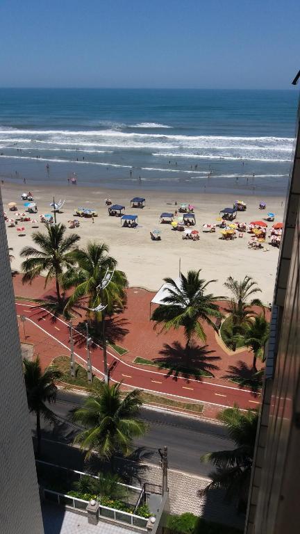 - une plage avec des voitures, des palmiers et l'océan dans l'établissement Apartamento na avenida da praia, à Praia Grande