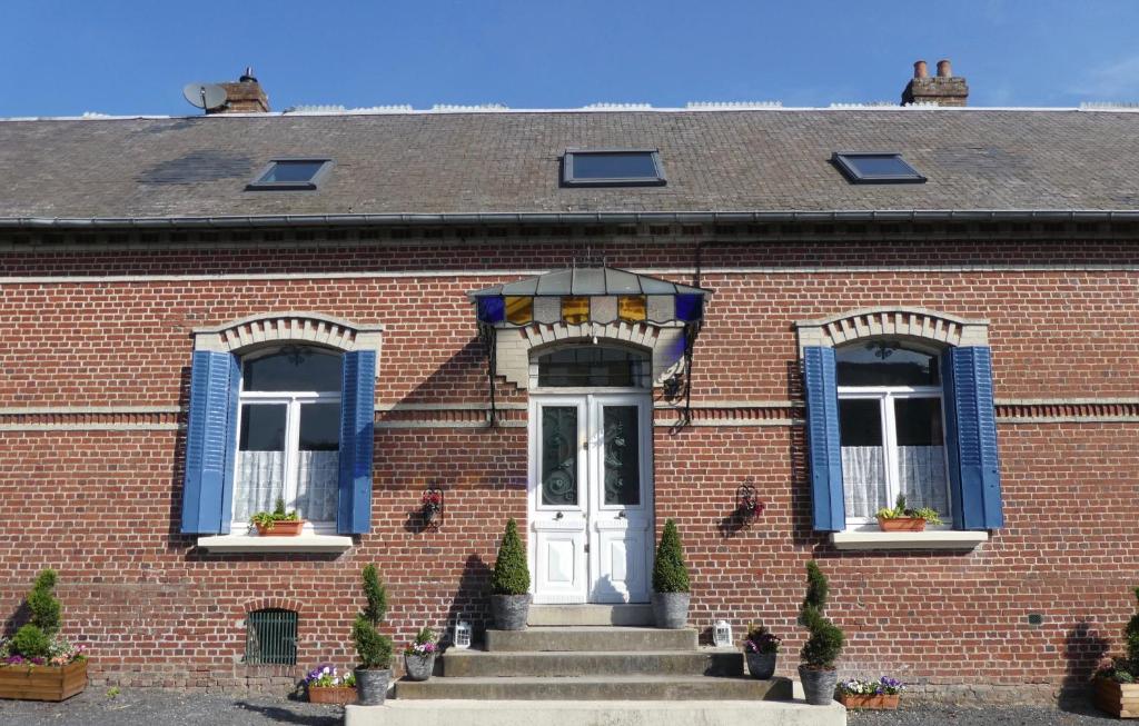 a brick building with a white door and blue windows at Guillemont Halt in Guillemont