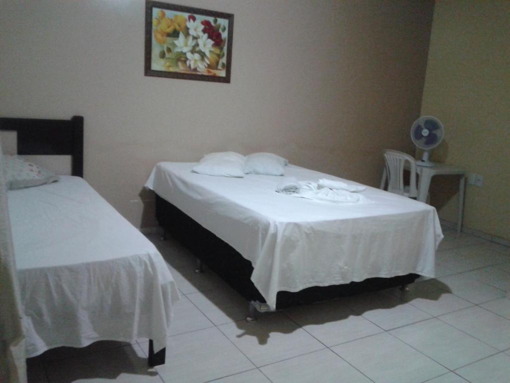 a room with two beds and a table with towels at Pousada Central in São Benedito