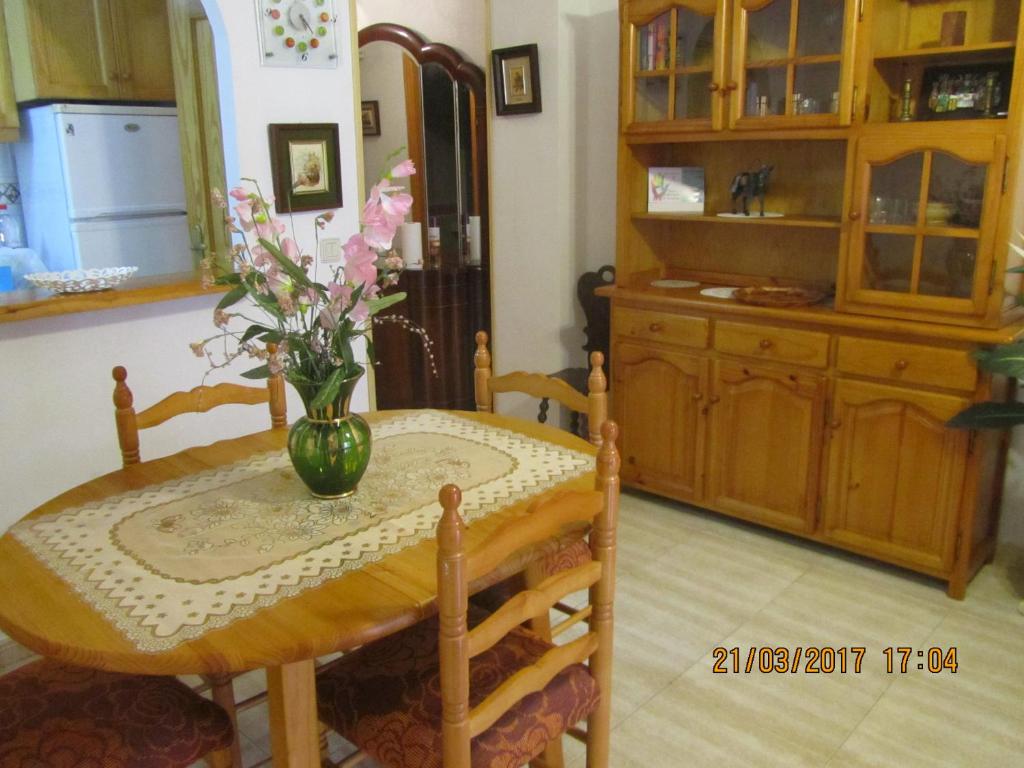 ein Esstisch mit einer Vase mit Blumen darauf in der Unterkunft los locos San Pascual in Torrevieja