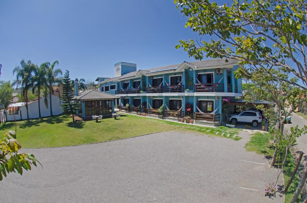 a large blue house with a car parked in the driveway at Mares do Sul Pousada in Garopaba