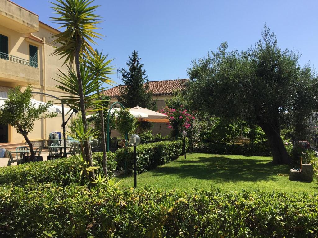 une cour avec des arbres et des buissons et un bâtiment dans l'établissement Albergo Marla, à Marina di Camerota
