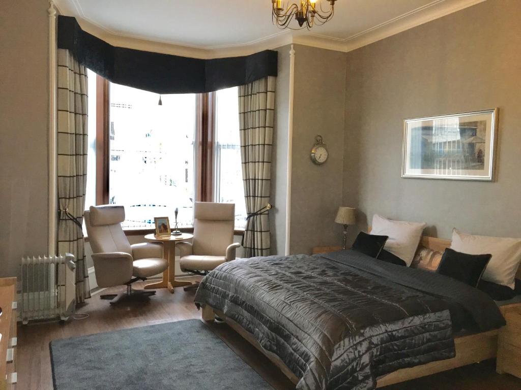 a bedroom with a bed and two chairs and a window at Hannahs Guesthouse in Aberdeen