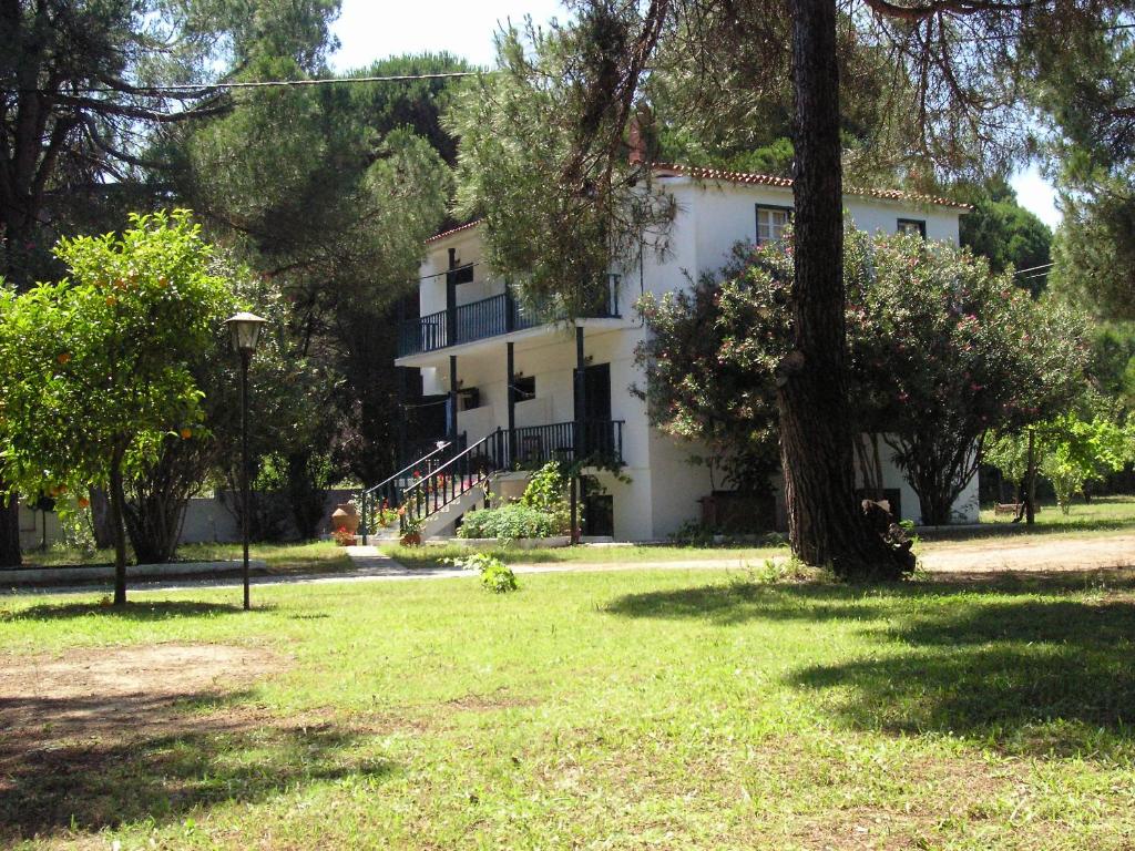 Una casa blanca con un árbol delante. en Strophilia Apartments, en Koukounaries