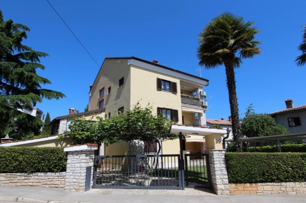 a house with a palm tree and a fence at Apartments Villa Mattossi in Rovinj