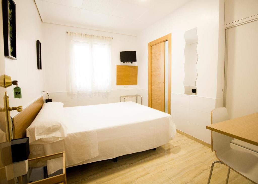 Habitación blanca con cama y ventana en Ravalencia I, en Valencia