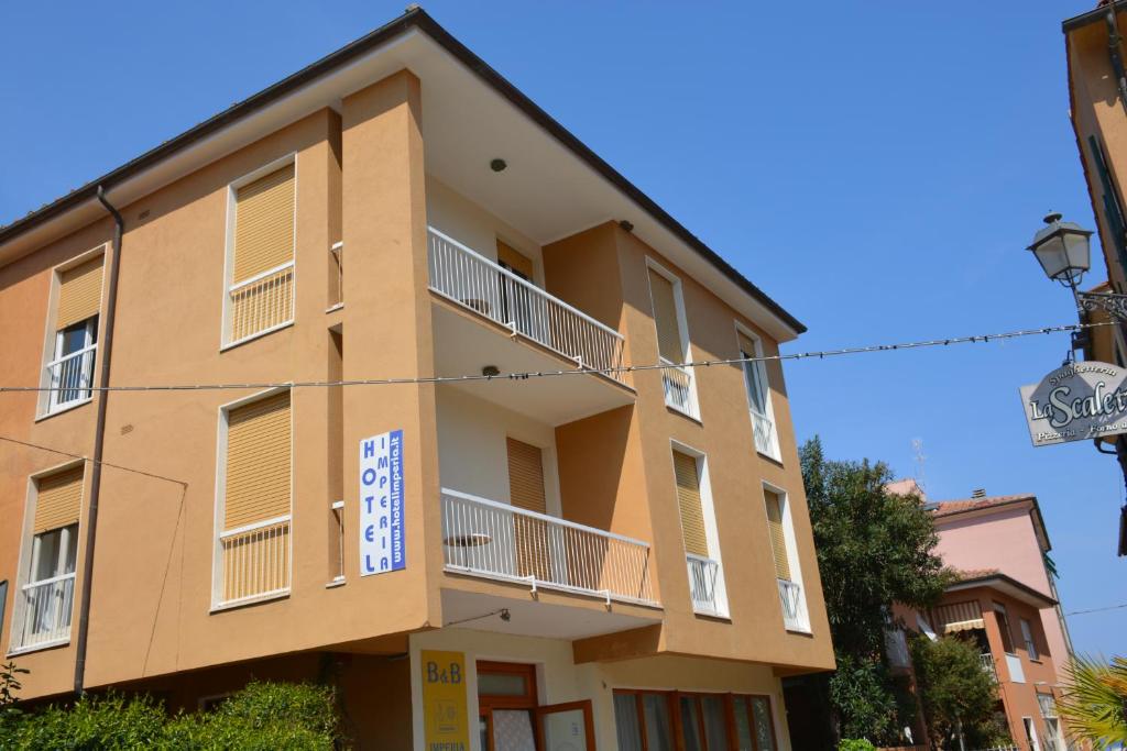 un edificio giallo con un cartello sopra di Hotel Imperia a Marciana Marina