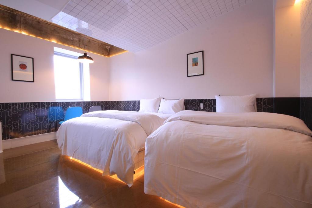 um quarto com 2 camas com lençóis brancos e uma janela em Hotel ONDO em Daegu