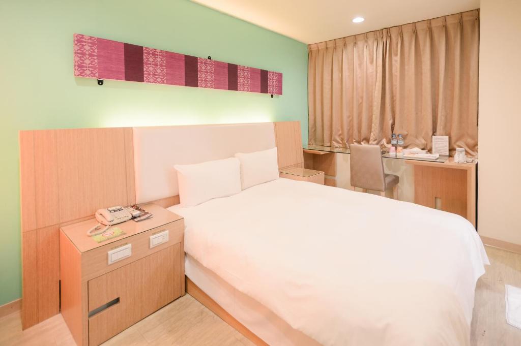 a bedroom with a bed and a desk with a phone at i-Deal Hotel in Taichung