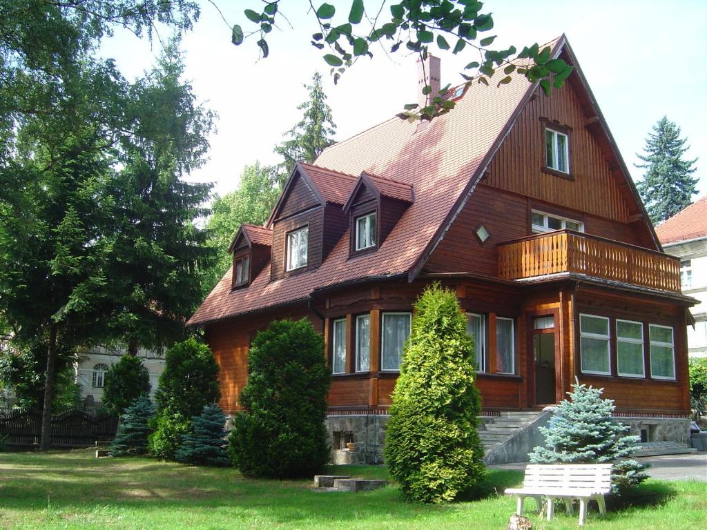 ein großes Holzhaus mit einer Bank davor in der Unterkunft Pokoje Gościnne Złota Palma in Lądek-Zdrój