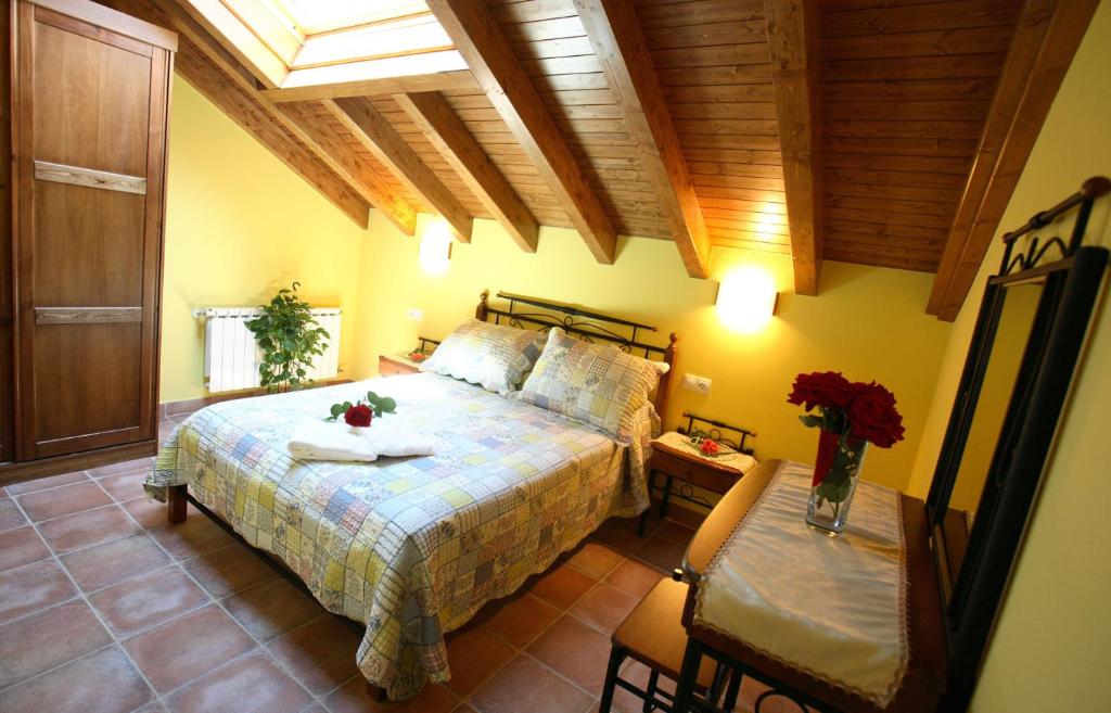 een slaapkamer met een bed en een tafel met bloemen erop bij Apartamentos Rurales La Viña in Cangas de Onís